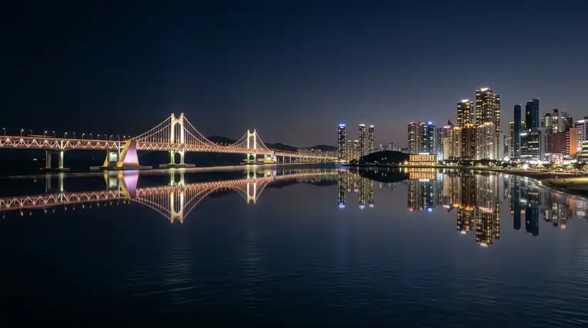 Panoramic long exposure of Busan skyline showing Marine City towers and Gwangandaegyo Bridge reflected in calm water
