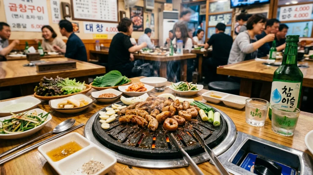 Beef and pork intestines grilling on tabletop with soju glasses