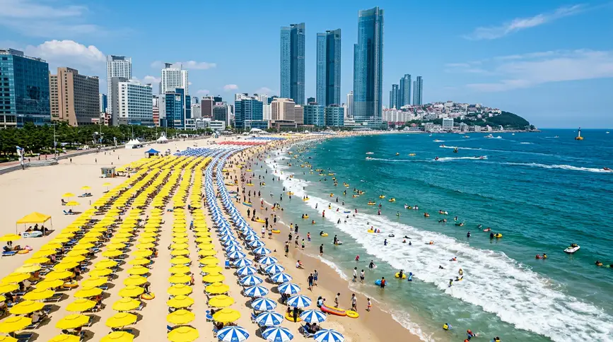 Thousands of bright yellow parasols on white sand with turquoise ocean and Marine City skyscrapers in background